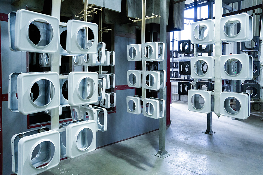 Multiple metal components with square frames hang from racks 