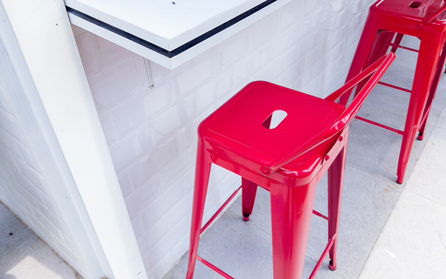 Two bright red metal bar stools are positioned by a white countertop