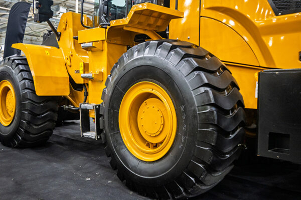 Close-up side view of a large yellow construction vehicle with big black tires