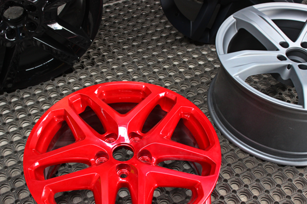 Three car wheel rims in different finishes—glossy black, matte gray, and shiny red
