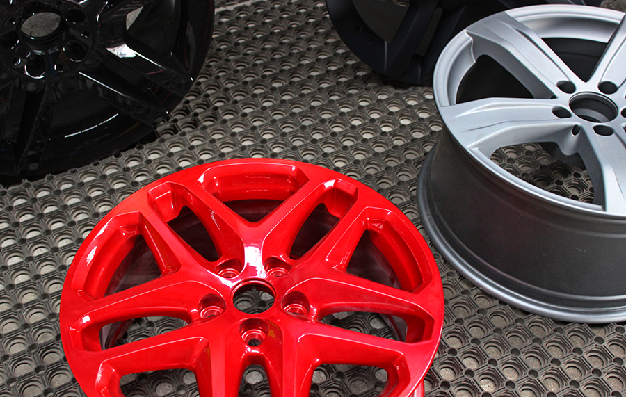 Three car wheel rims in different finishes—glossy black, matte gray, and shiny red